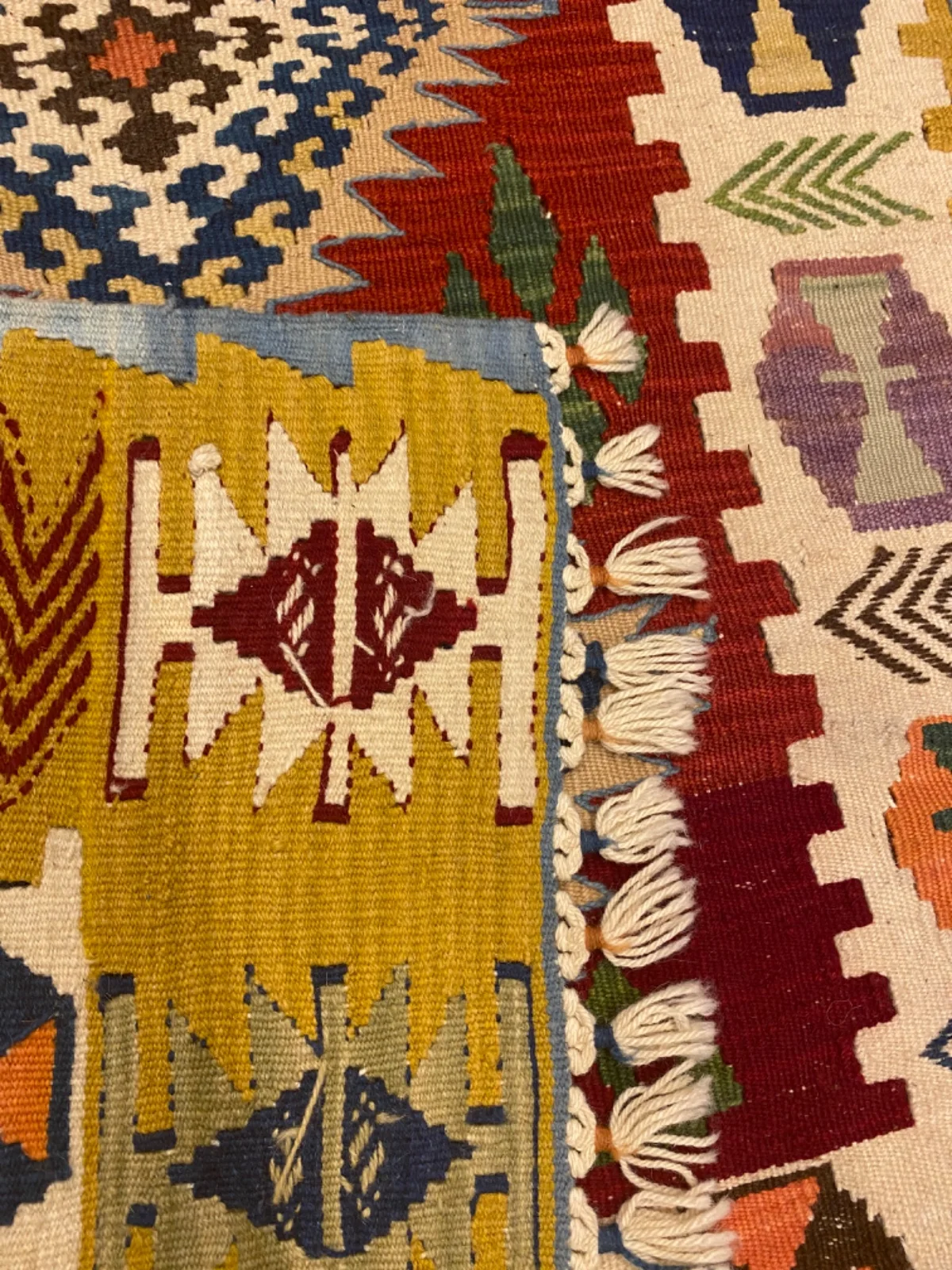 Sarı bordürlü kilimin geometrik motifleri ve püsküllü kenarı
